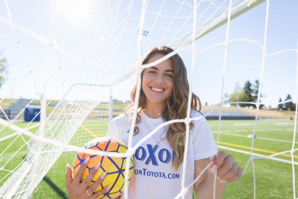 senior girl with soccer ball net and sun flare